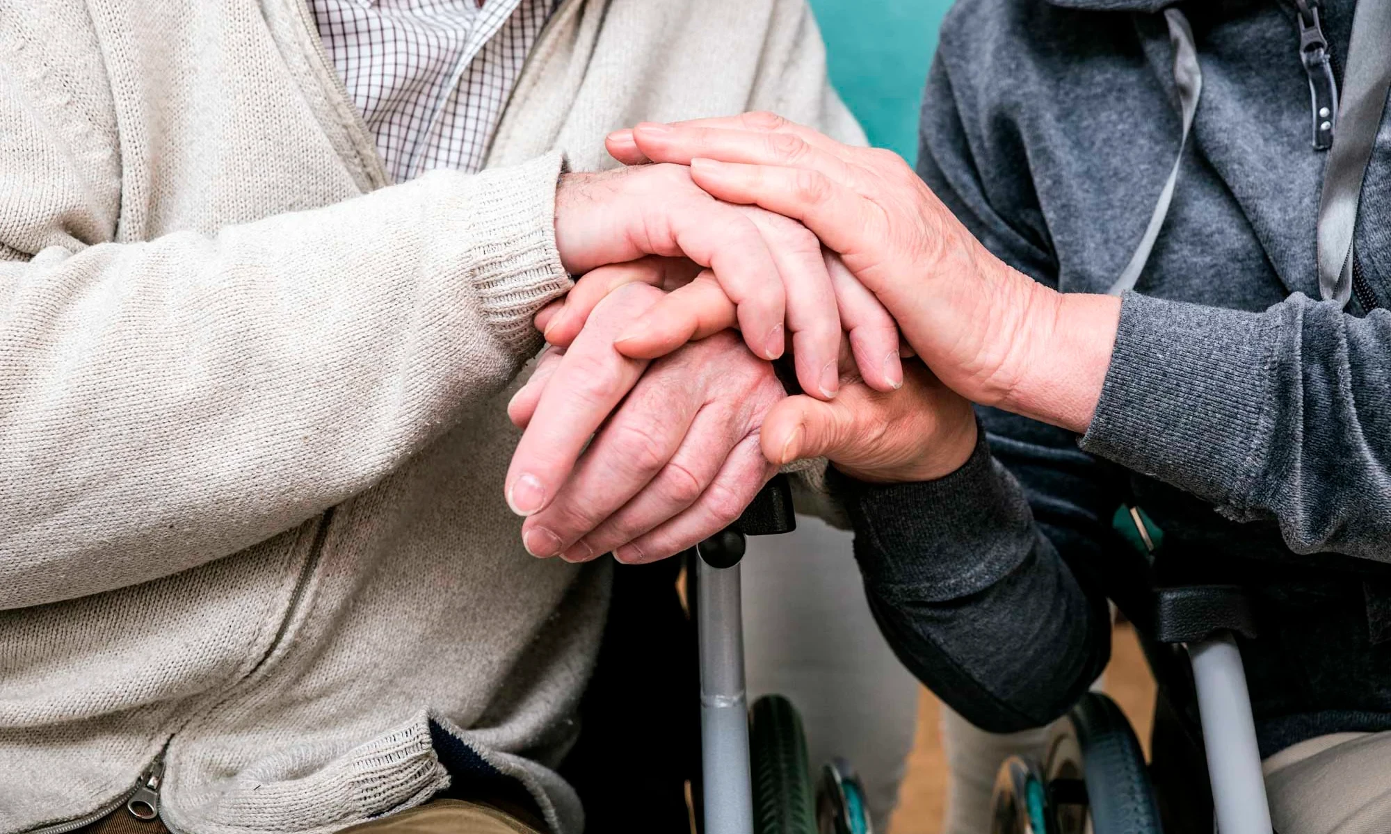 Leistungen in der Pflege – unterstützende Hand in der Betreuung Symbolbild für Leistungen in der Pflege: Zwei Personen halten sich unterstützend die Hände