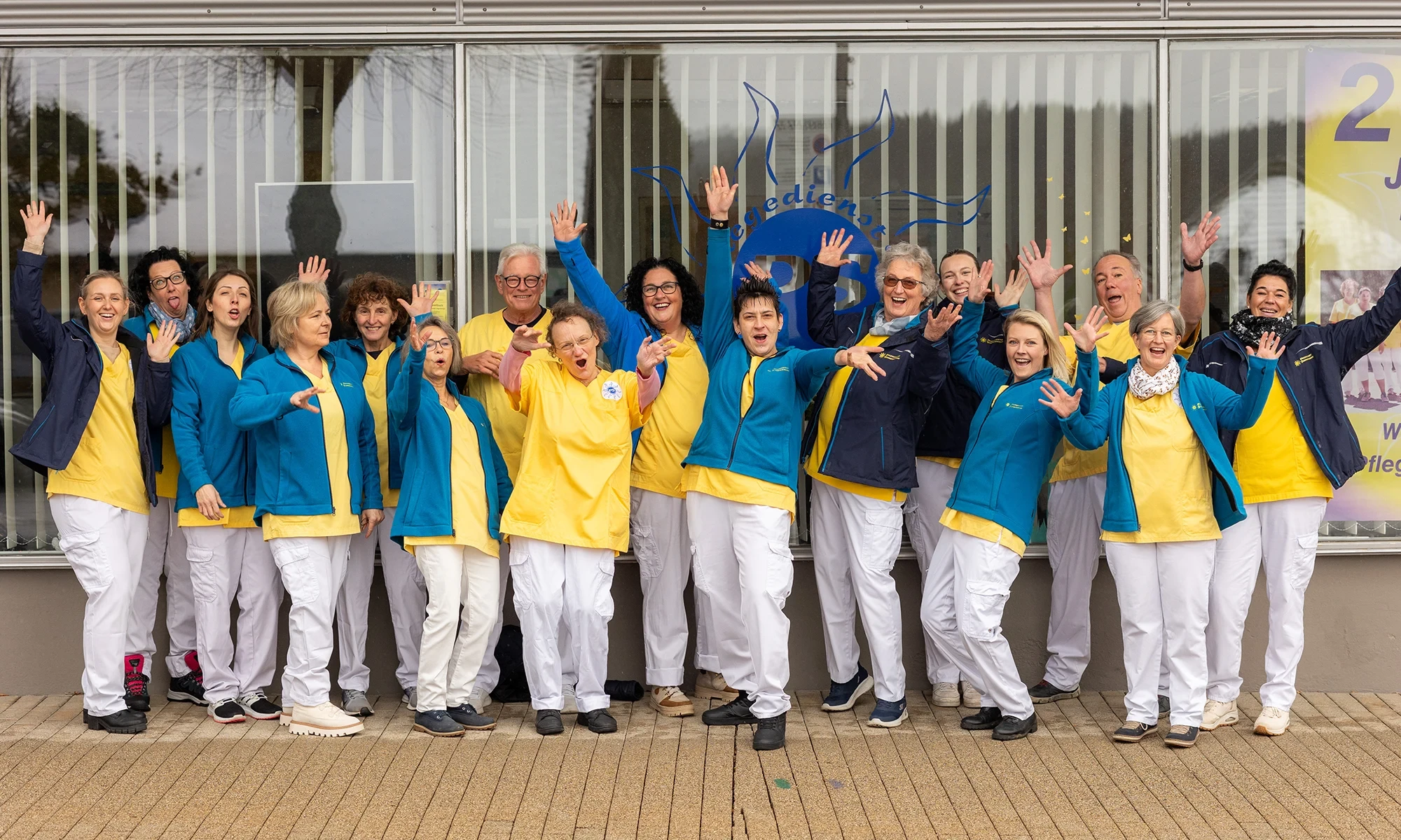 Über uns – Das Team des Pflegedienstes stellt sich vor Teamfoto eines Pflegedienstes vor dem Büro mit gelben und blauen Uniformen