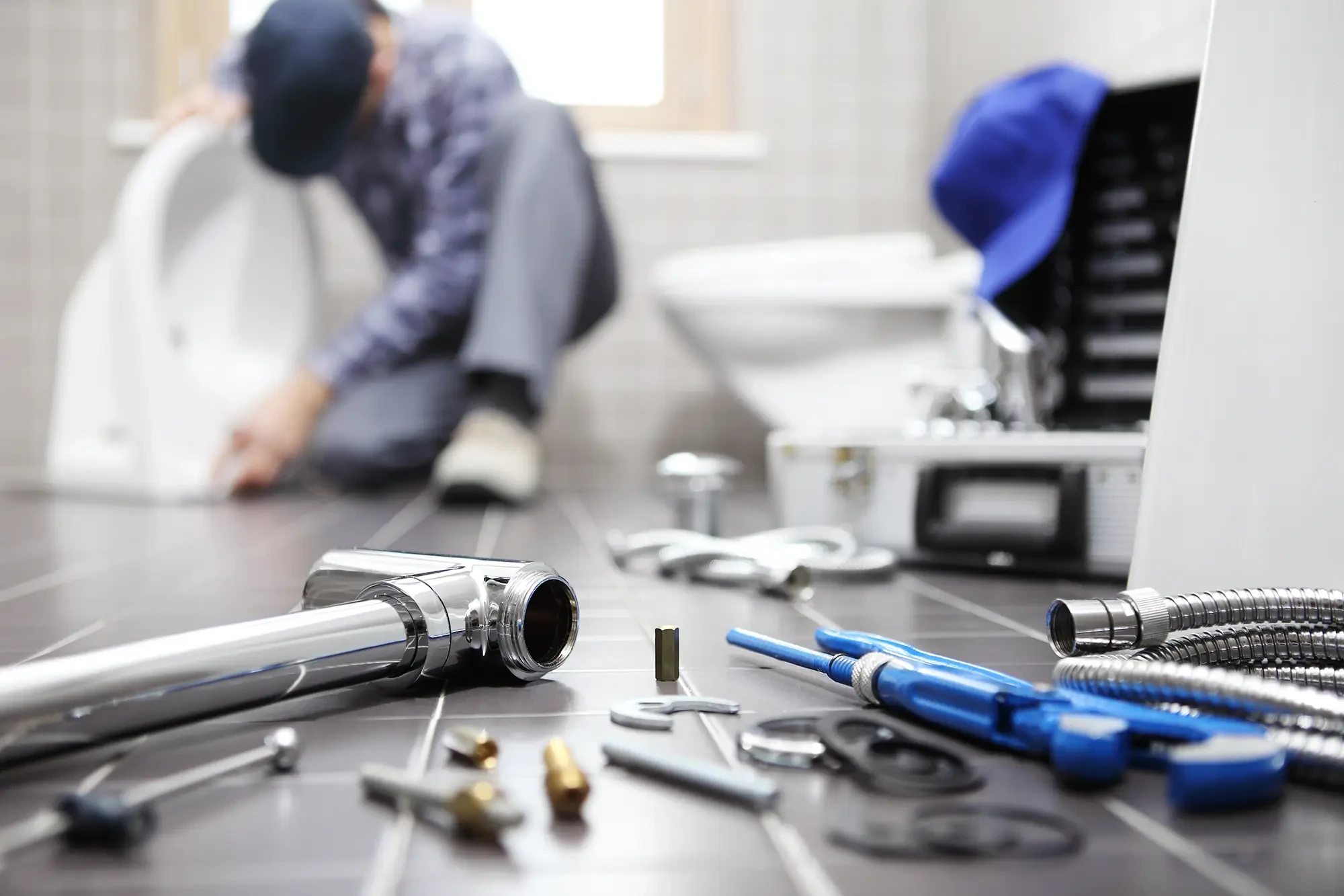 Sanitärinstallateur arbeitet im Badezimmer – Headerbild Startseite Sanitärinstallateur bei der Arbeit im Badezimmer mit Werkzeugen auf dem Boden