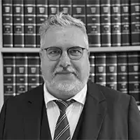 Matthias Frank vor Bücherregal in Schwarz-Weiß, Business-Outfit