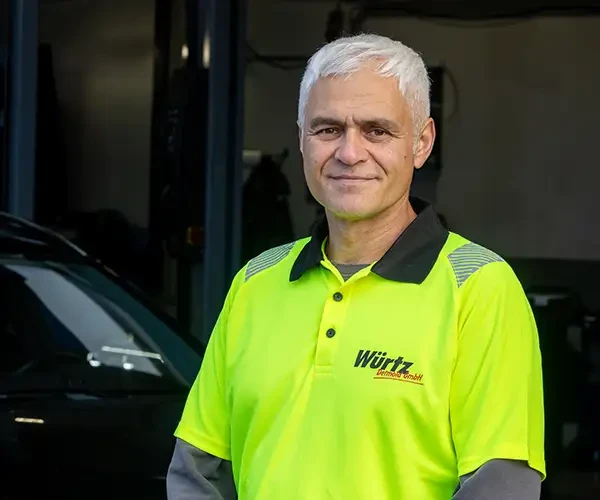 Uemit Sert von Würtz GmbH in Arbeitskleidung vor einem Fahrzeug