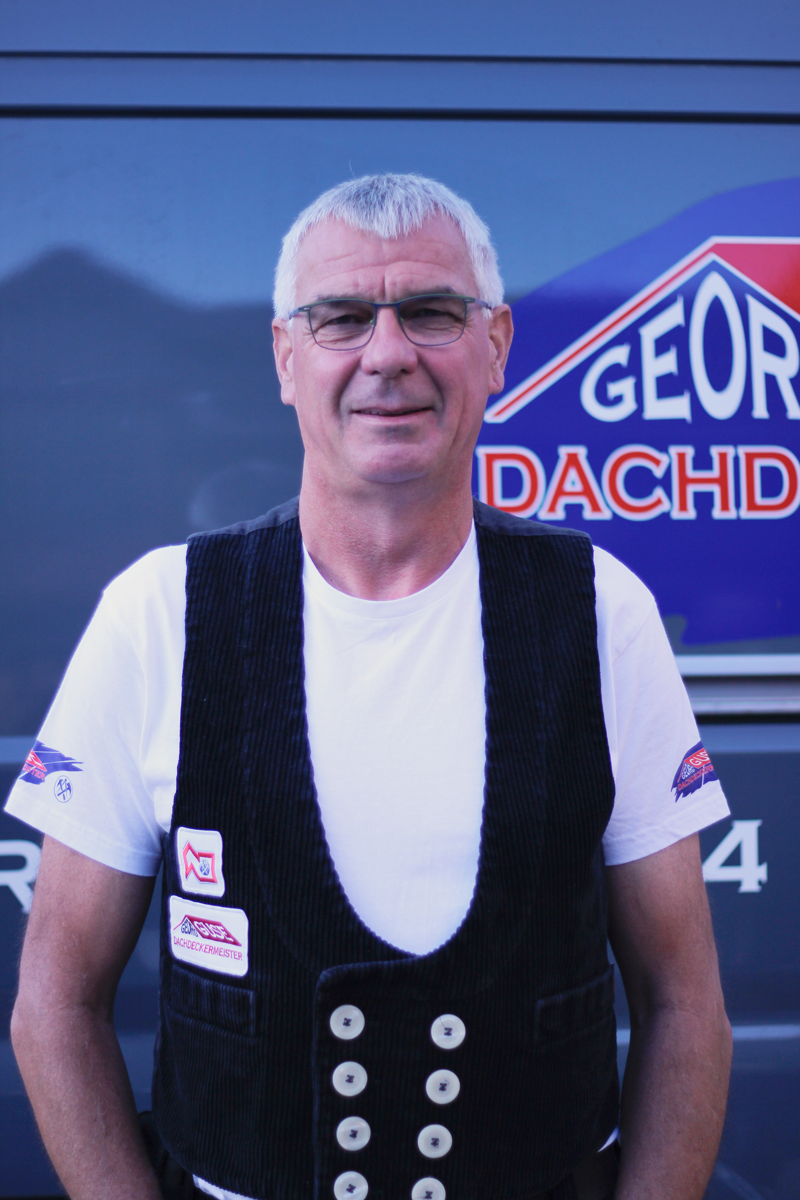 Dachdeckermeister Georg Guse vor Firmenfahrzeug mit Logo