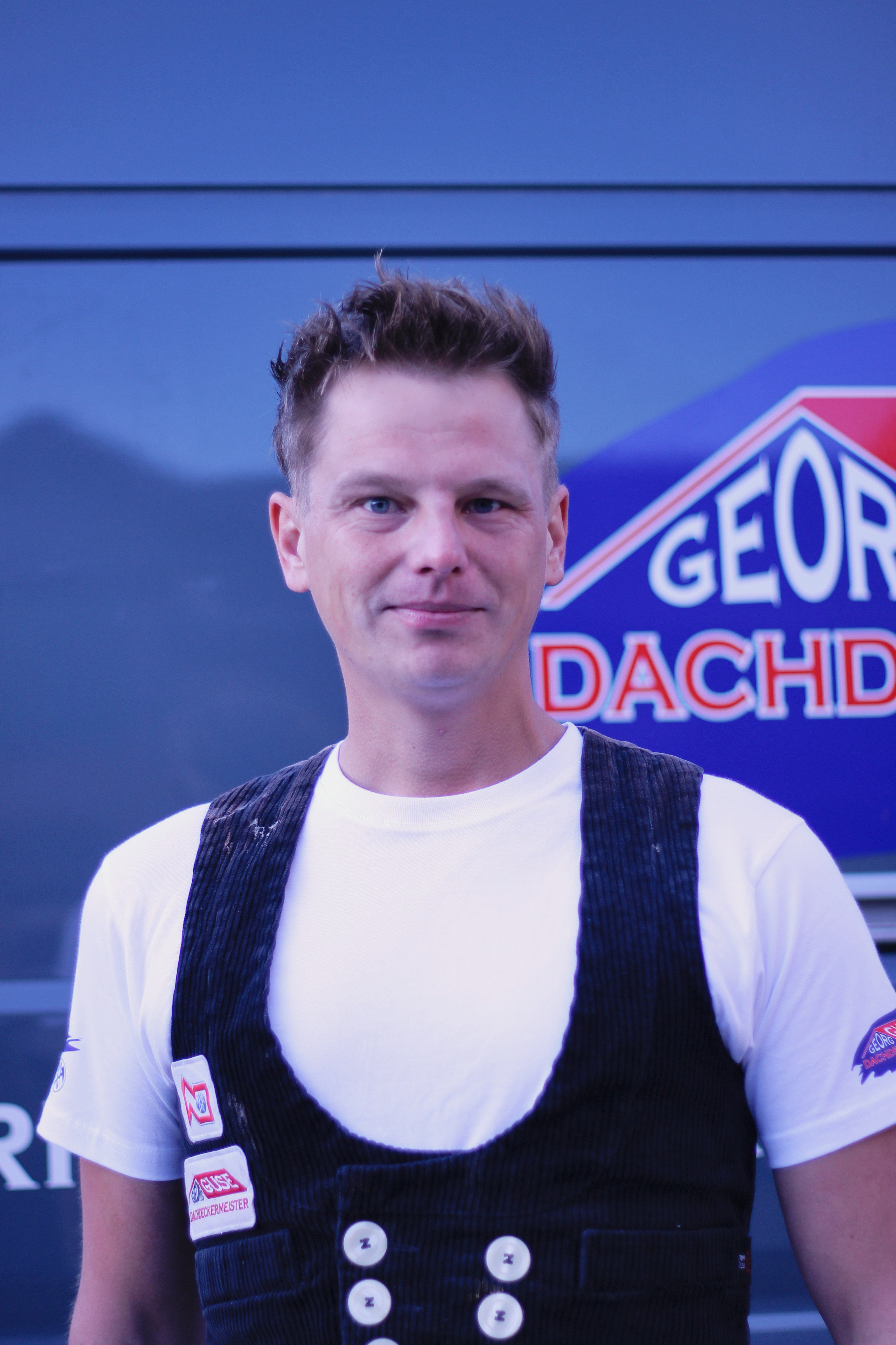 Azubi Marvin Garz vor Firmenfahrzeug der Dachdeckerei Georg