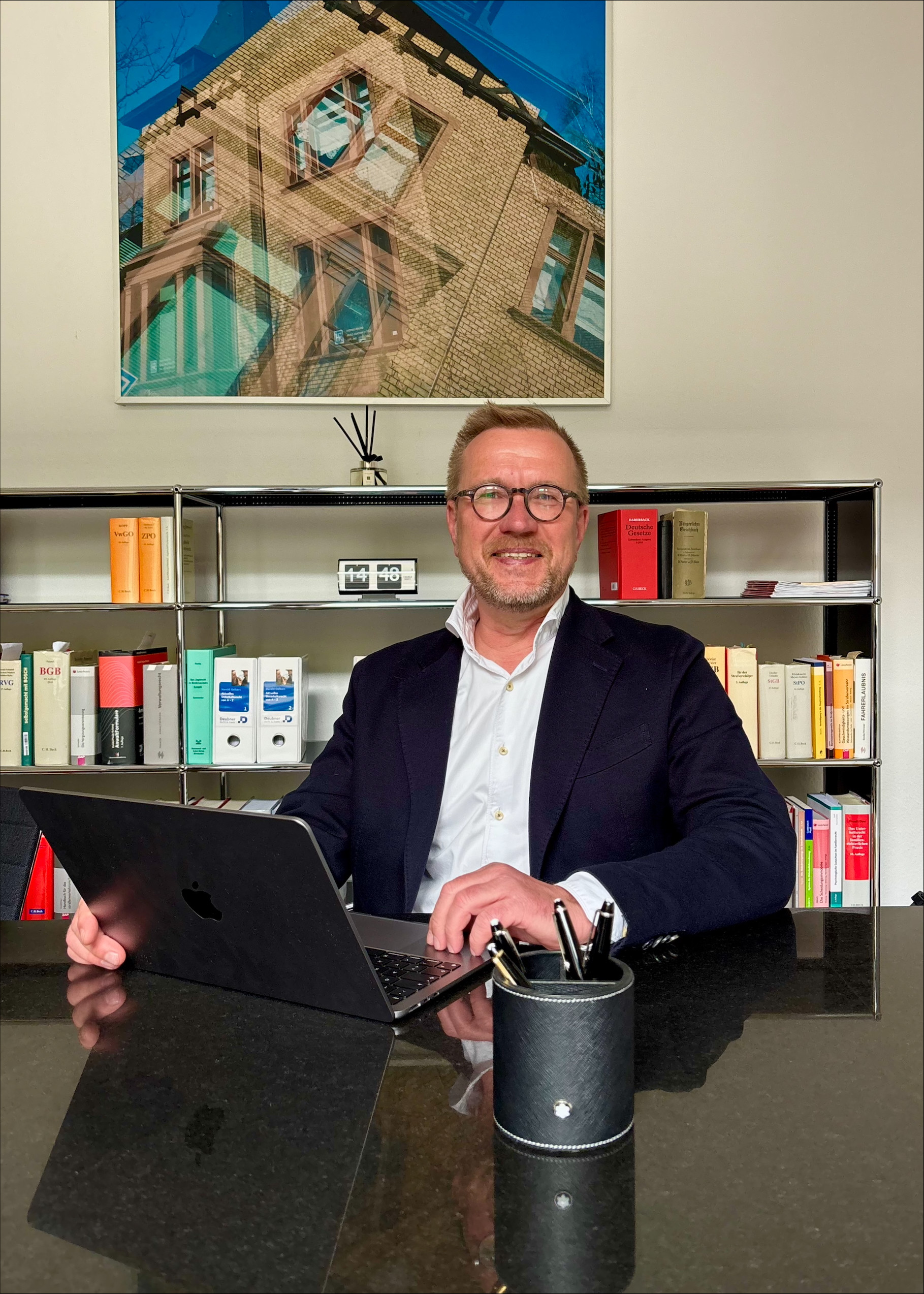 Mann im Büro mit Laptop vor Bücherregal