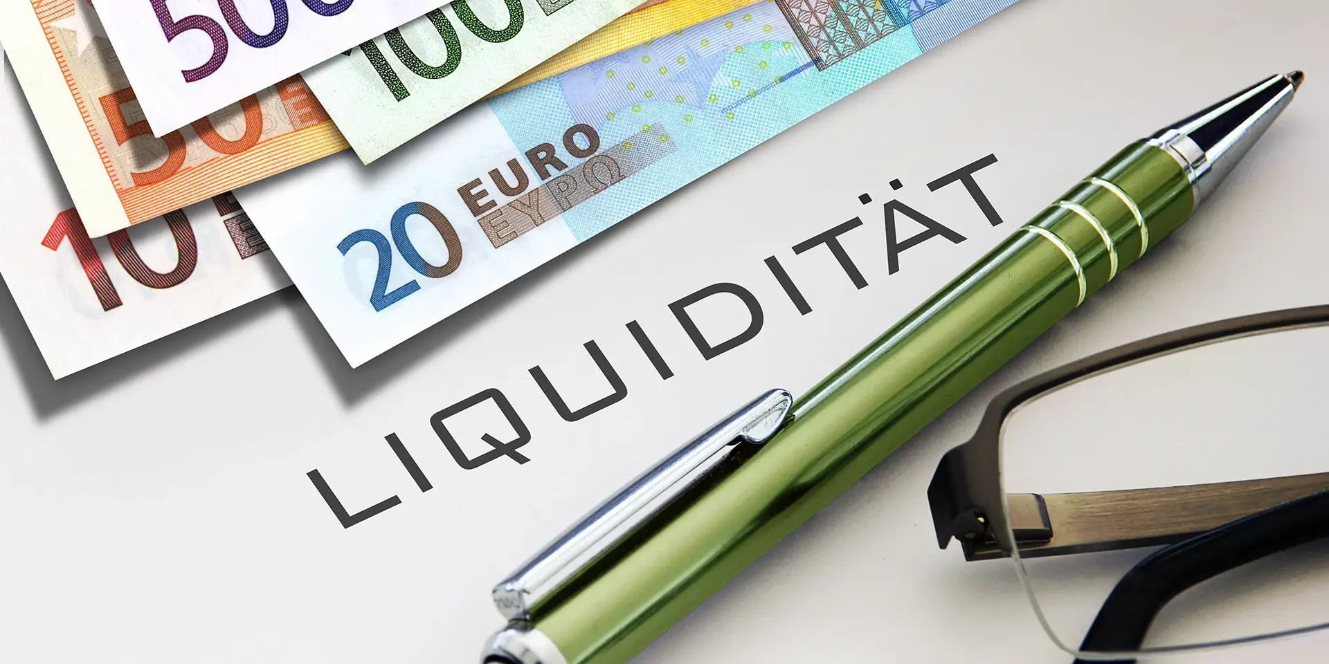 Header-Bild mit Euro-Geldscheinen, Stift und dem Schriftzug Liquidität