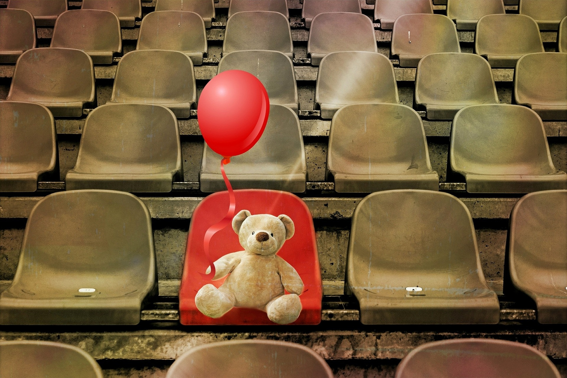 Unbesetzter Sitzplatz im Stadion mit Teddybär und rotem Ballon