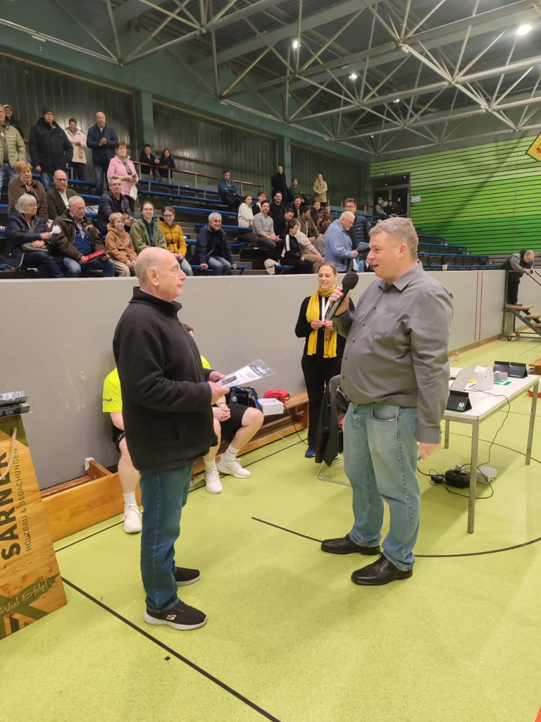 Ehrung bei einer Sportveranstaltung in einer Turnhalle mit Zuschauern im Hintergrund