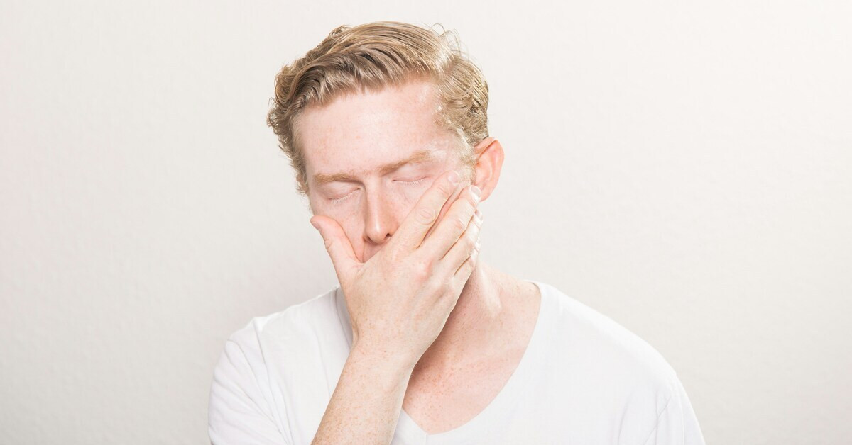 Mann mit Kiefergelenkschmerzen hält seine Hand an die Wange