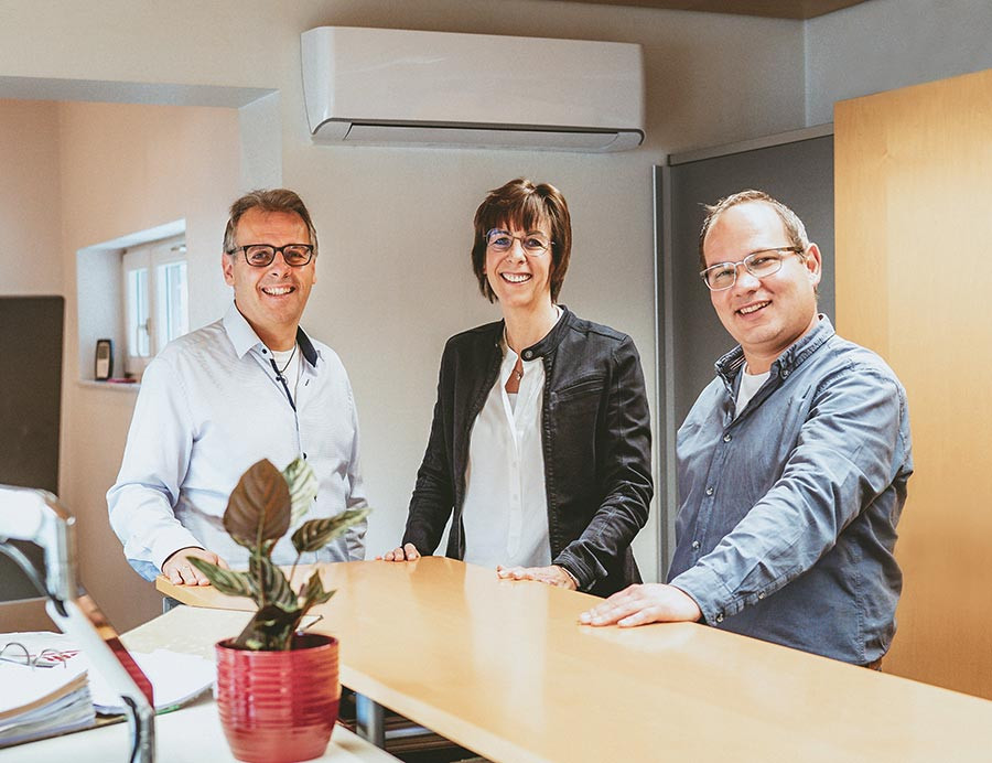 Teamfoto in einem modernen Büro in Lichtenberg, drei Personen am Empfangstresen