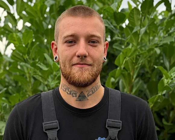 Porträt von Fabian Toepfer im Grünen, mit Tattoos und Piercings