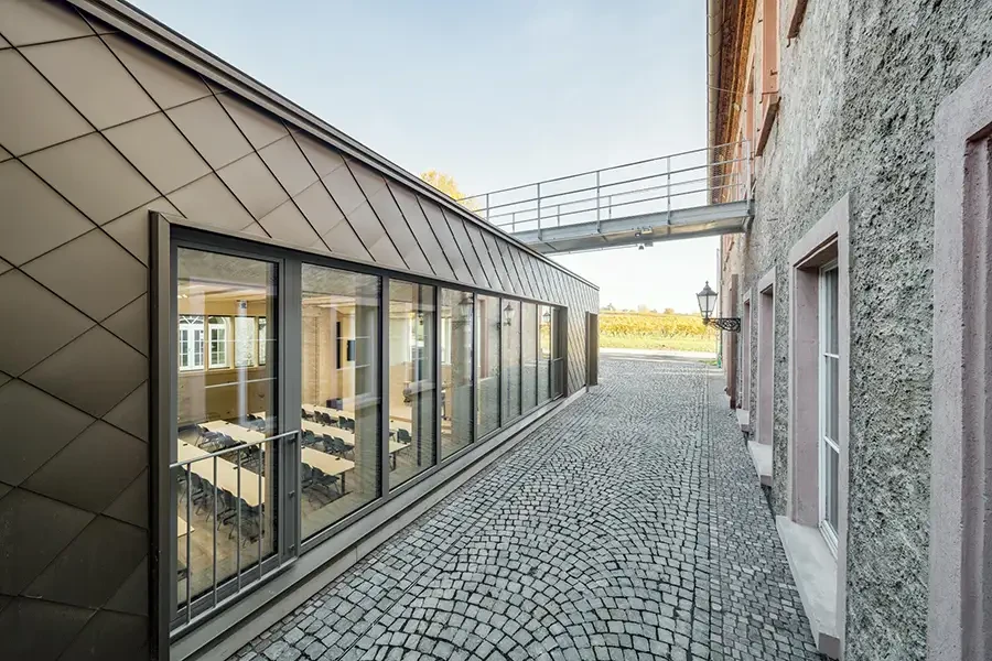 Modernes Gebäude mit Glasfassade und Kopfsteinpflaster, Verbindungsgang zwischen zwei Gebäuden