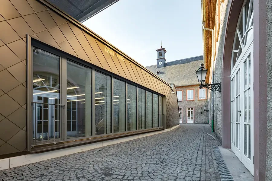 Moderne Architektur trifft auf historische Gebäude in einer Altstadt mit Kopfsteinpflaster und Uhrturm