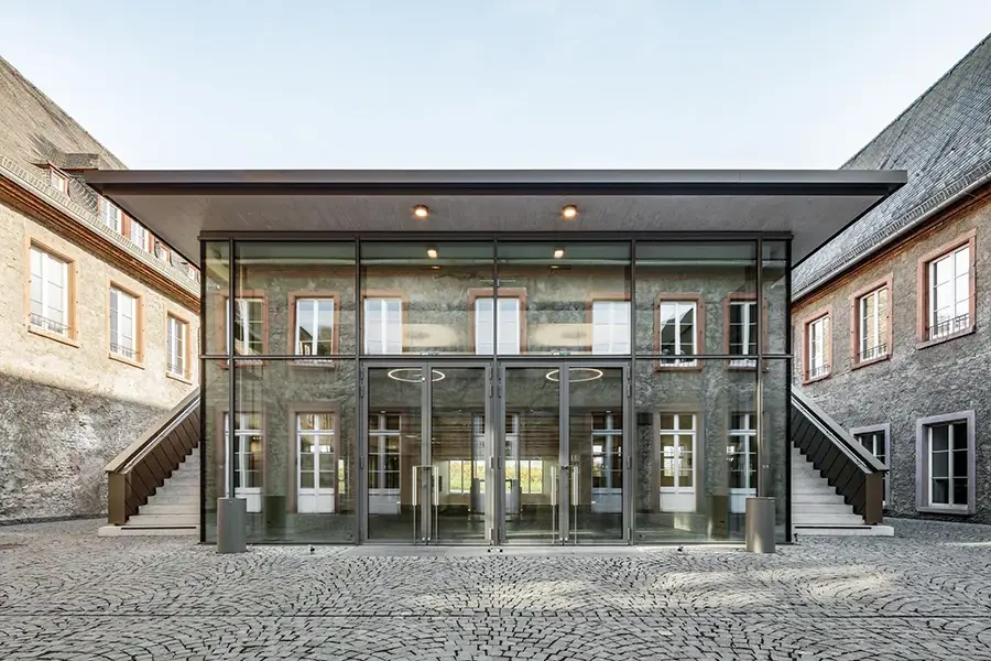 Moderne Glasfassade eines Gebäudes mit Kopfsteinpflaster im Vordergrund