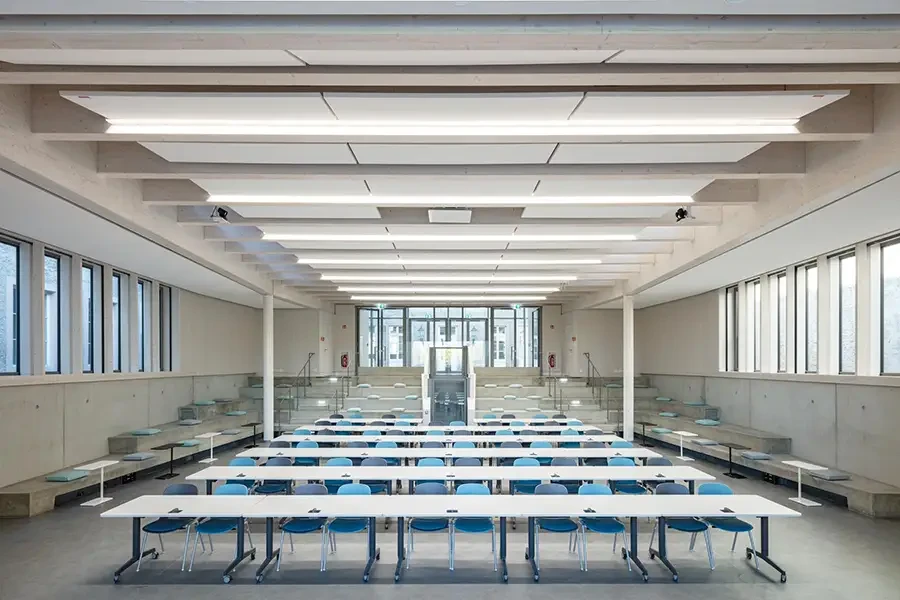 Moderner, heller Hörsaal mit blauen Stühlen und weißen Tischen in einem Universitätsgebäude