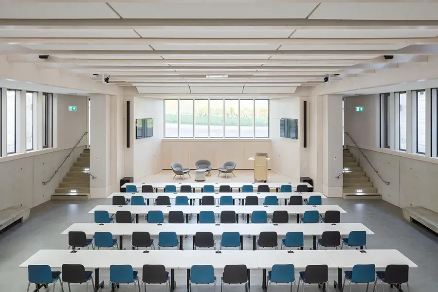 Moderner, heller Konferenzraum mit Reihenbestuhlung, Podium und großen Fenstern