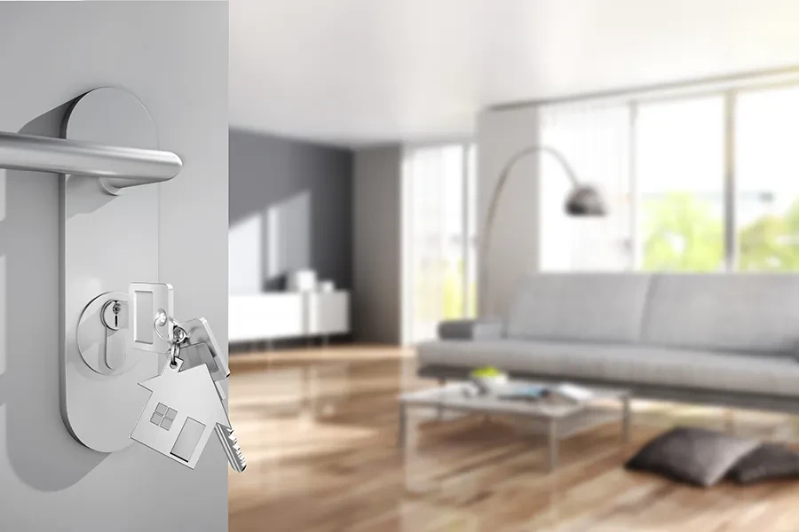 Teaserbild Radon – Schlüssel in Tür einer modernen Wohnung als Symbol für Radonschutz Schlüssel mit Hausanhänger in moderner Wohnungstür als Teaser für Radon-Thema