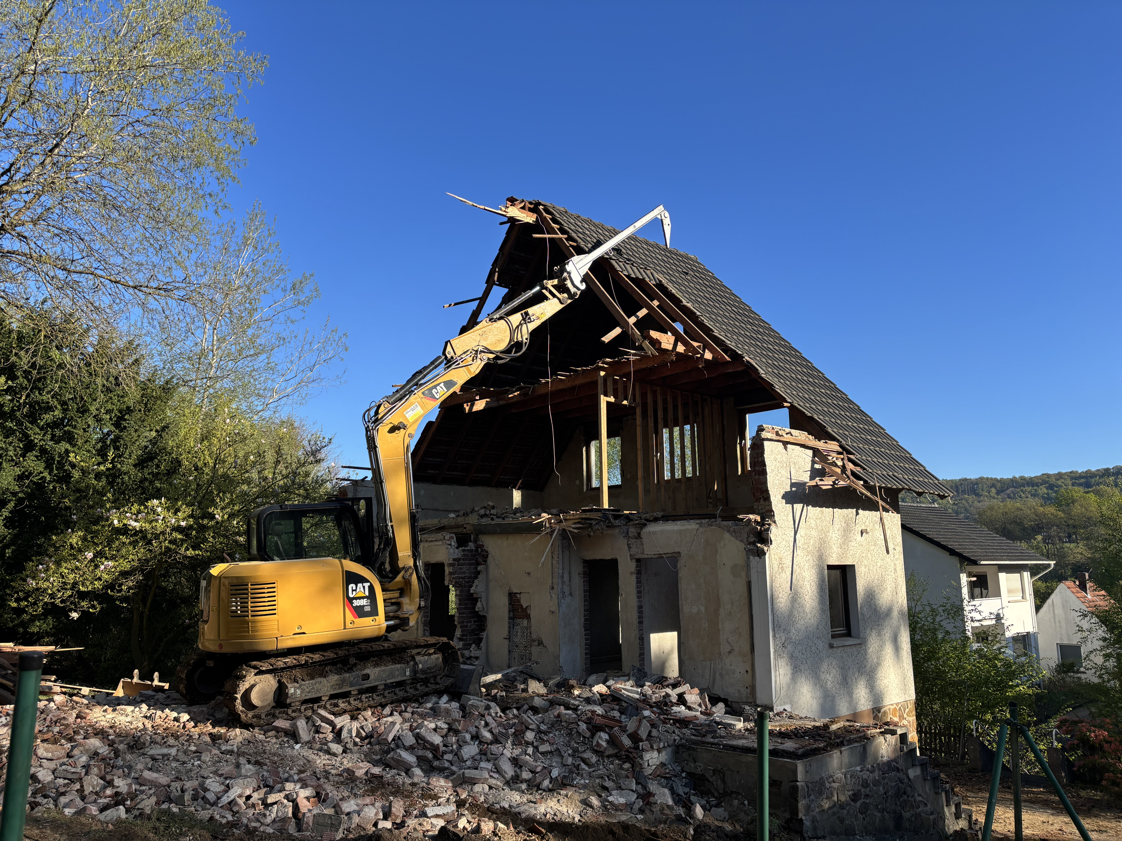 Bagger beim Abriss eines alten Hauses an einem sonnigen Tag