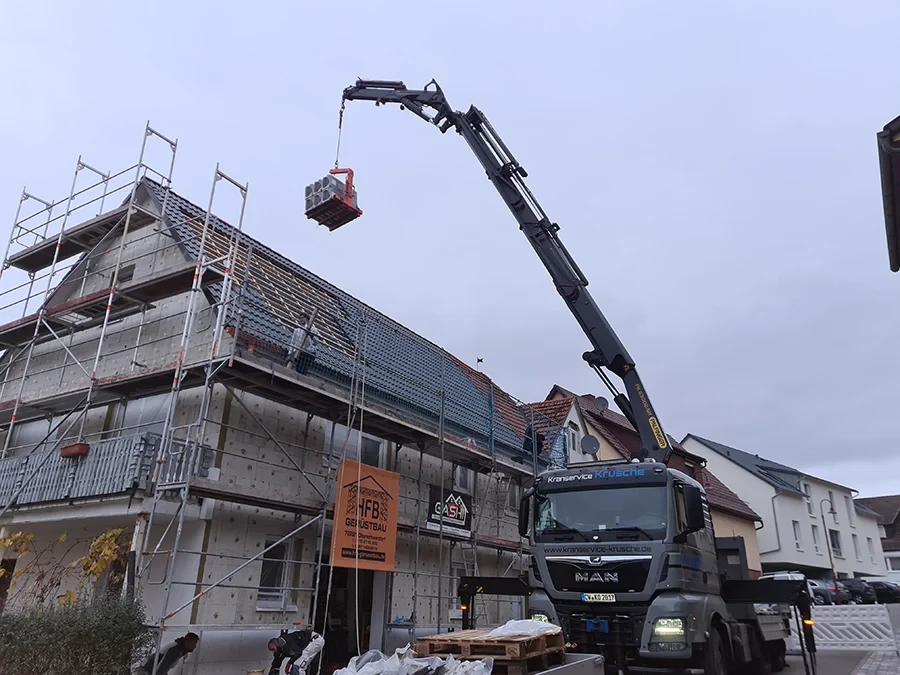 Krandienst beim Hausbau – Kranservice Krusche hebt Baumaterial auf ein Gerüst