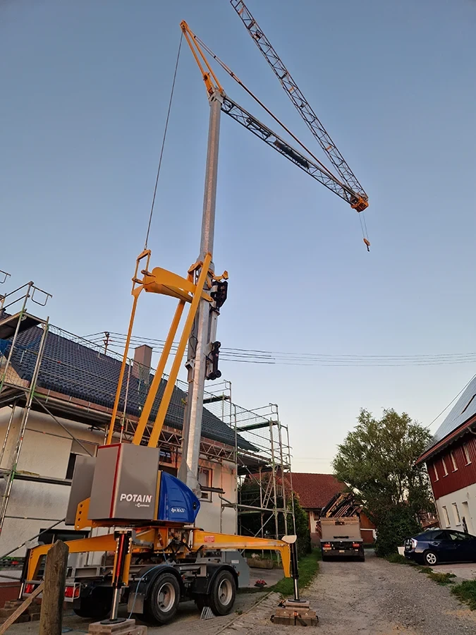 Krandienst mit Potain Baukran bei Hausbau, Montagearbeiten am Kranmast