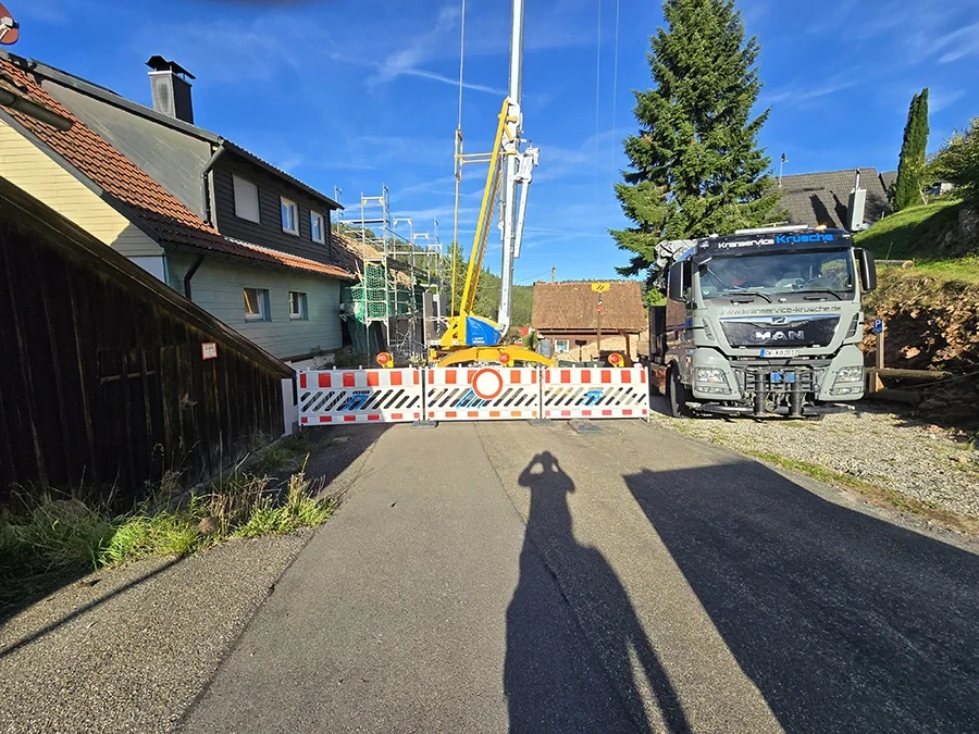 Krandienst im Einsatz bei einer Baustelle mit Kran und LKW von Krusche, Straßensperrung im Wohngebiet