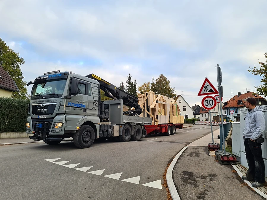 Spezialtransport mit Anhänger von Krusche Kranservice in einer Wohnstraße, Transport von Holzelementen
