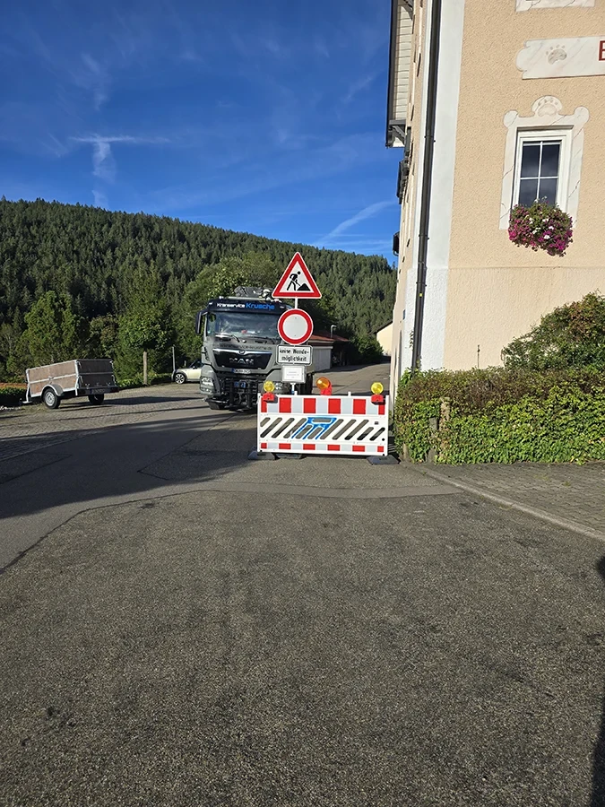 Spezialtransport mit Anhänger vor Straßensperrung in ländlicher Umgebung
