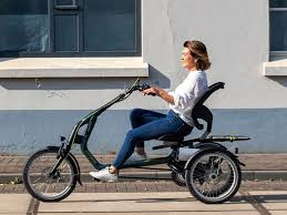 Frau fährt ein EasyRider Compact 2 Dreirad vor einer Hauswand