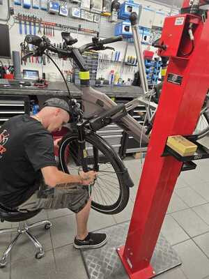 Fahrradmechaniker bei der Reparatur eines E-Bikes in einer modernen Werkstatt