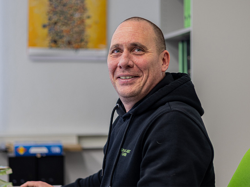 Portrait von Roger im modernen Web-Layout, sitzend im Büro