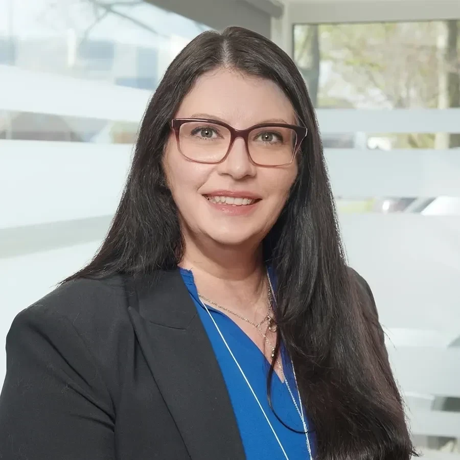 Karina Klima im Business-Outfit mit Brille, Portraitfoto vor modernem Hintergrund