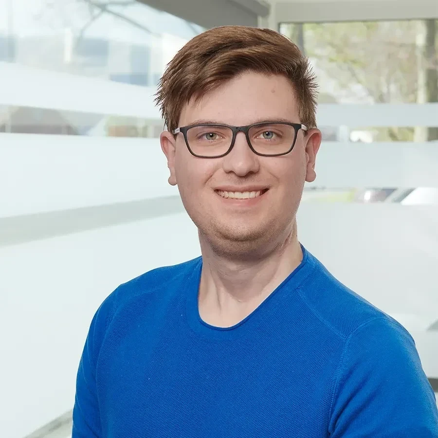 Porträt von Luca Klima mit Brille und blauem Pullover
