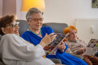 Senioren sitzen gemeinsam auf dem Sofa und lesen eine Zeitschrift in gemütlicher Atmosphäre
