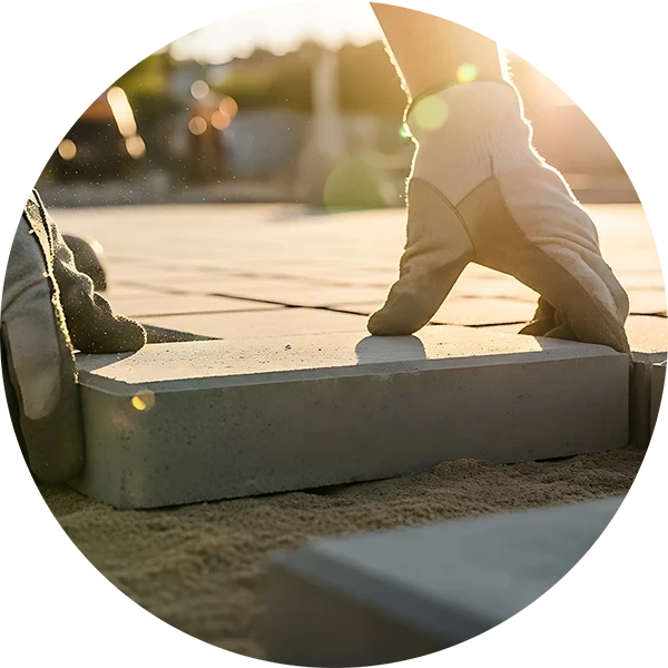 Handwerker verlegt Pflastersteine auf Sandbett bei Sonnenlicht