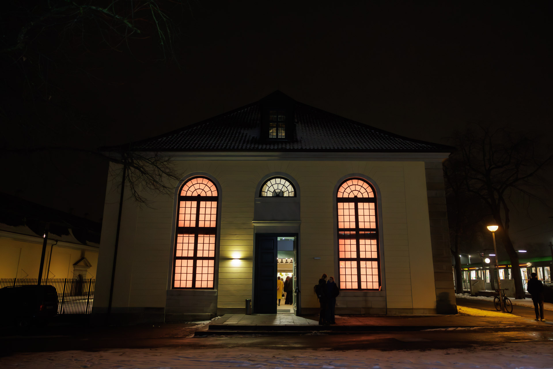 Orangerie bei Nacht mit beleuchteten Fenstern und gefneter Tr