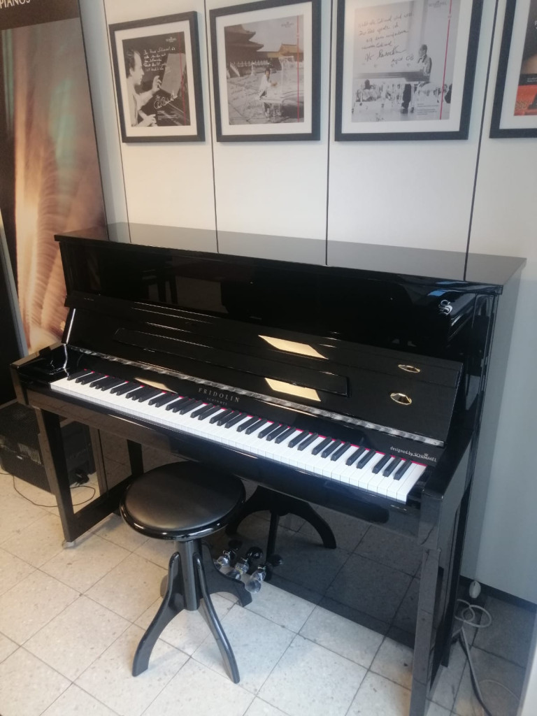 Fridolin Klavier in schwarzem Hochglanz-Finish mit Klavierhocker in einem Musikraum