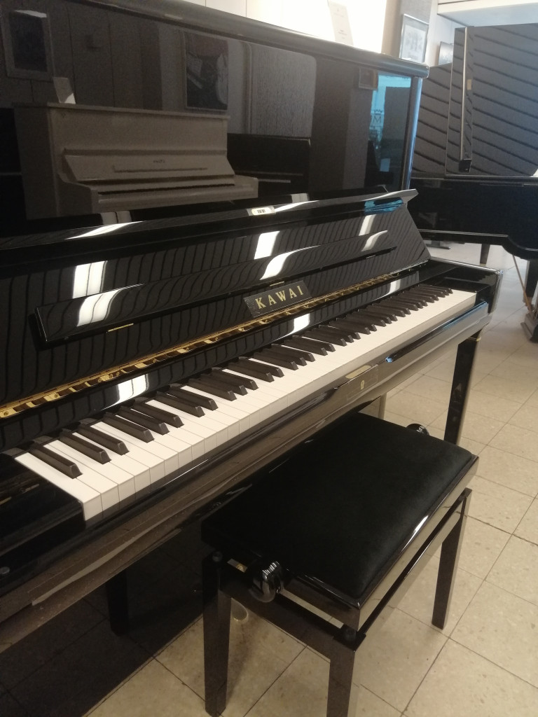 Kawai Klavier in einem Musikgeschäft, Nahaufnahme der Klaviatur und des Klavierhockers