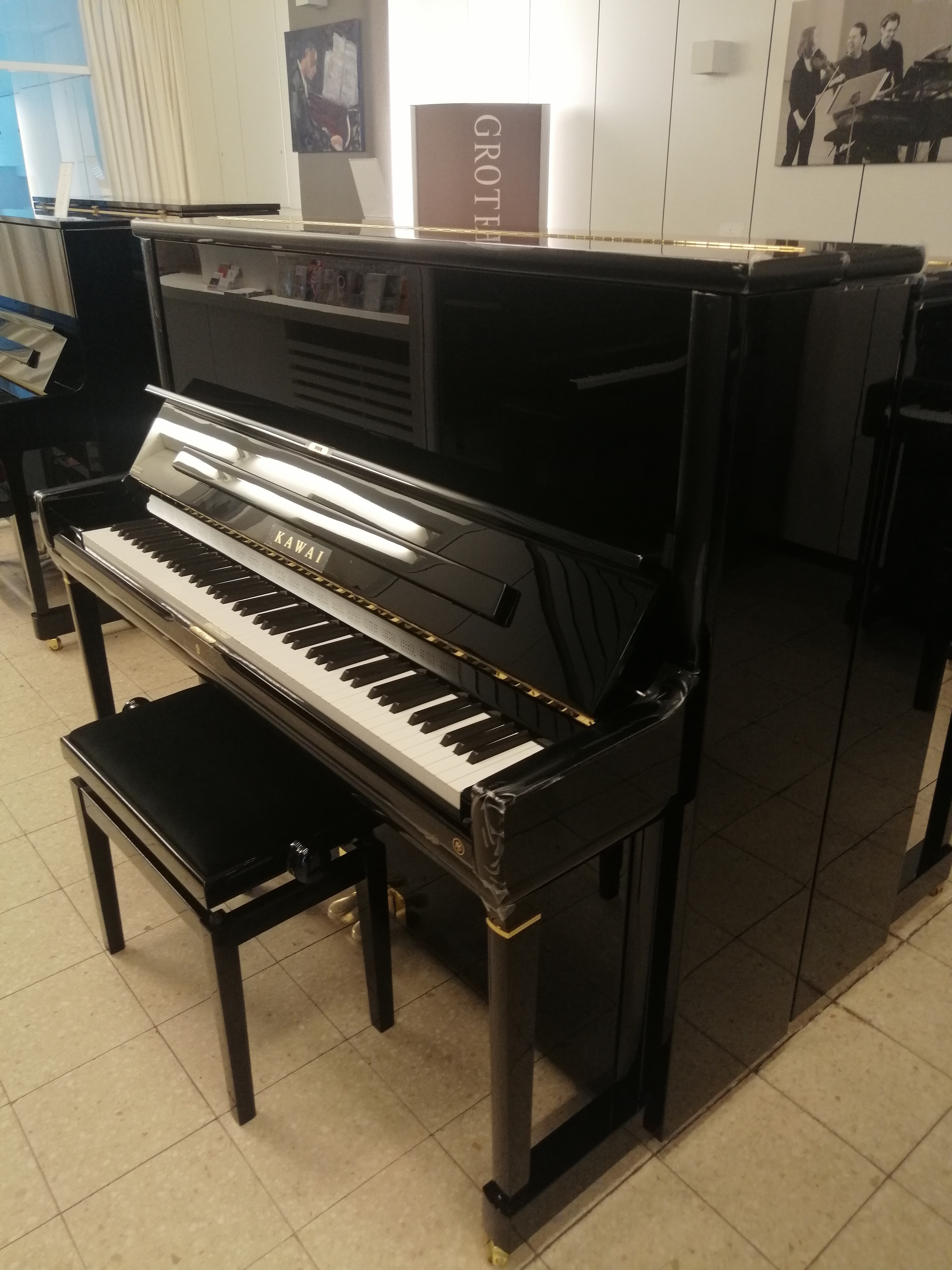 Schwarzes Kawai Klavier mit Klavierbank in einem Musikgeschäft
