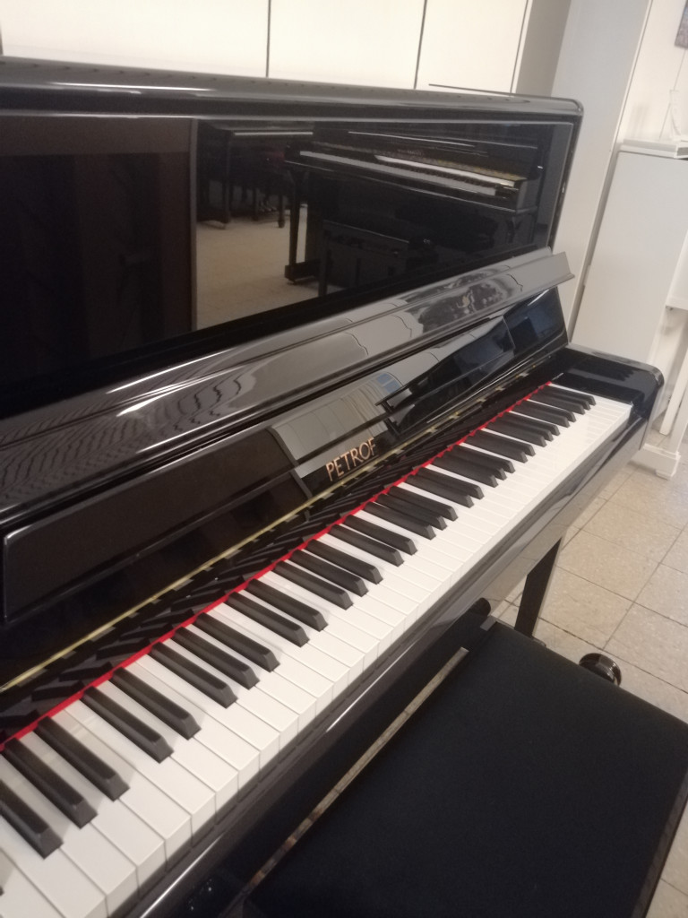 Schwarzes Petrof Klavier in einem Musikraum, Nahaufnahme der Klaviatur