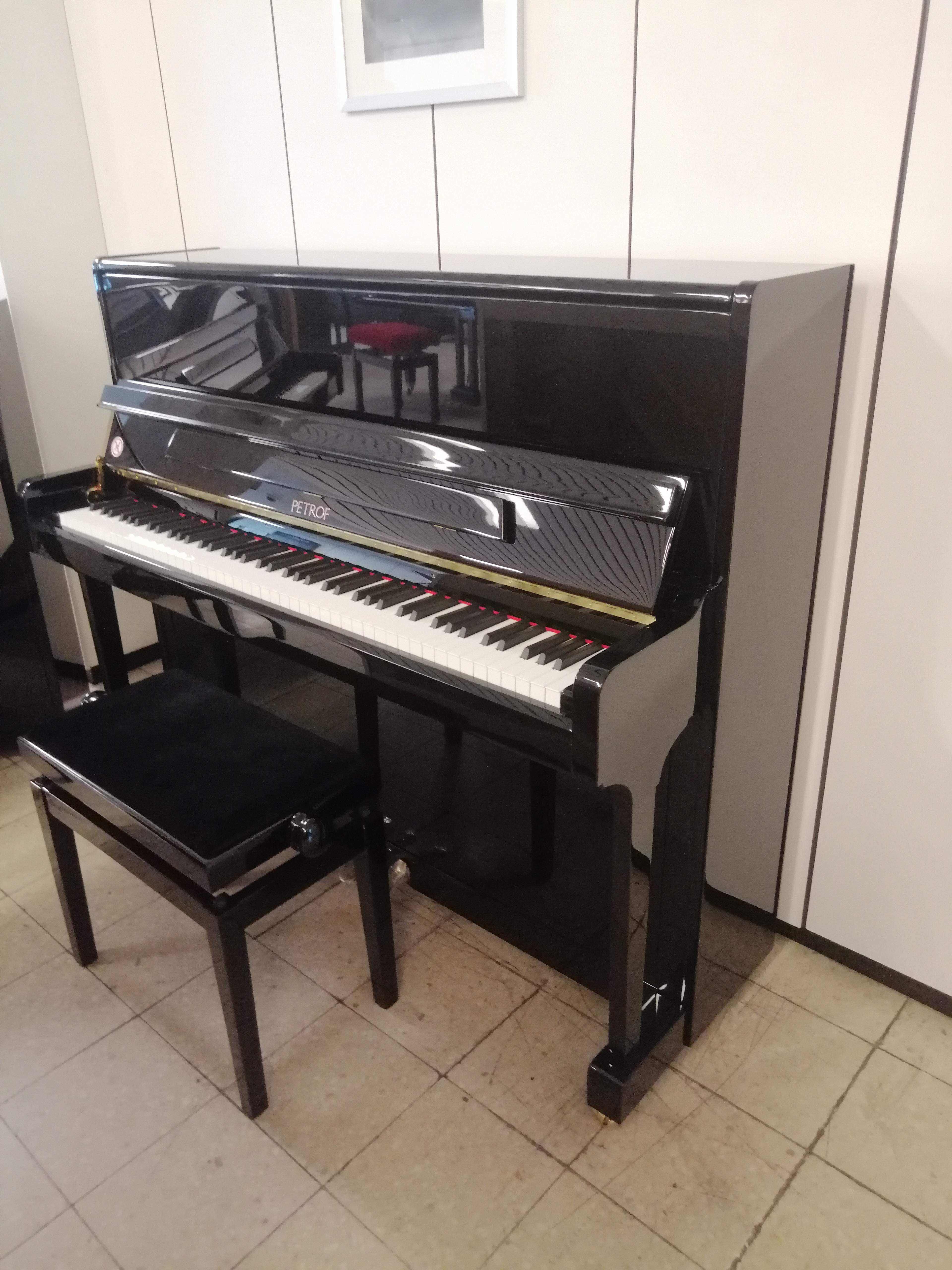 Schwarzes Petrof Klavier mit Klavierbank in modernem Raum
