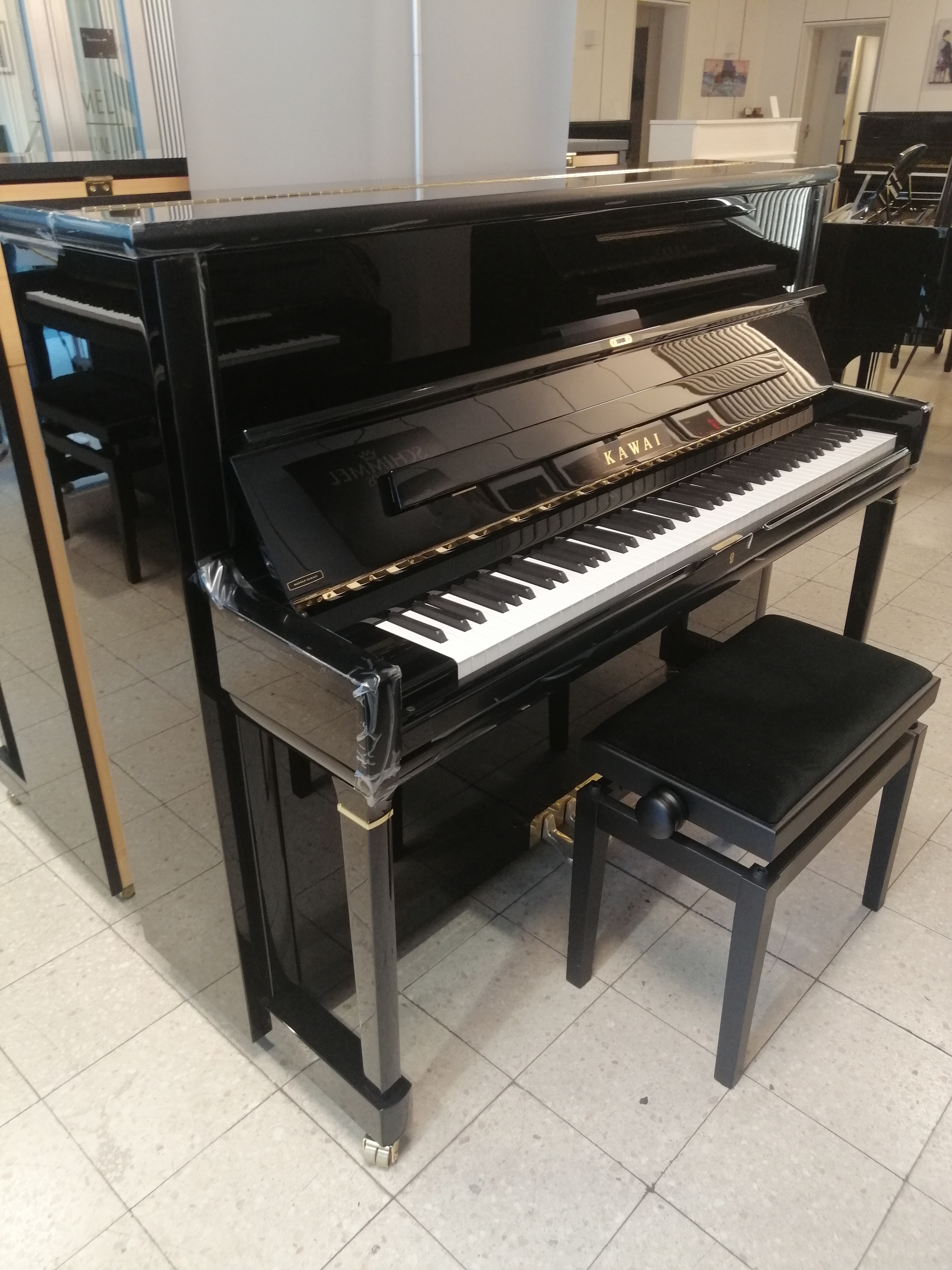 Schwarzes Kawai Klavier mit Klavierbank in einem Musikgeschäft