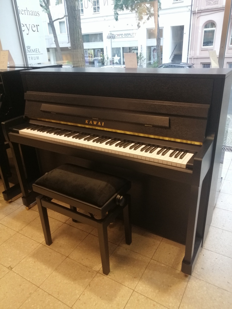 Kawai Klavier Upright Piano schwarz im Musikgeschäft Kawai Klavier in einem Musikgeschäft, modernes schwarzes Upright Piano mit Klavierbank