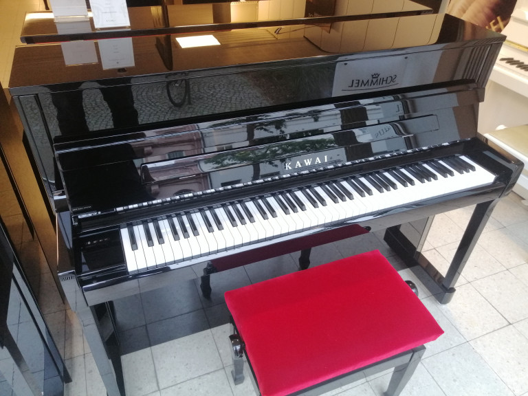 Kawai Klavier mit roter Klavierbank im Musikgeschäft – img-20260826-151801.jpg Schwarzes Kawai Klavier mit roter Klavierbank in einem Musikgeschäft