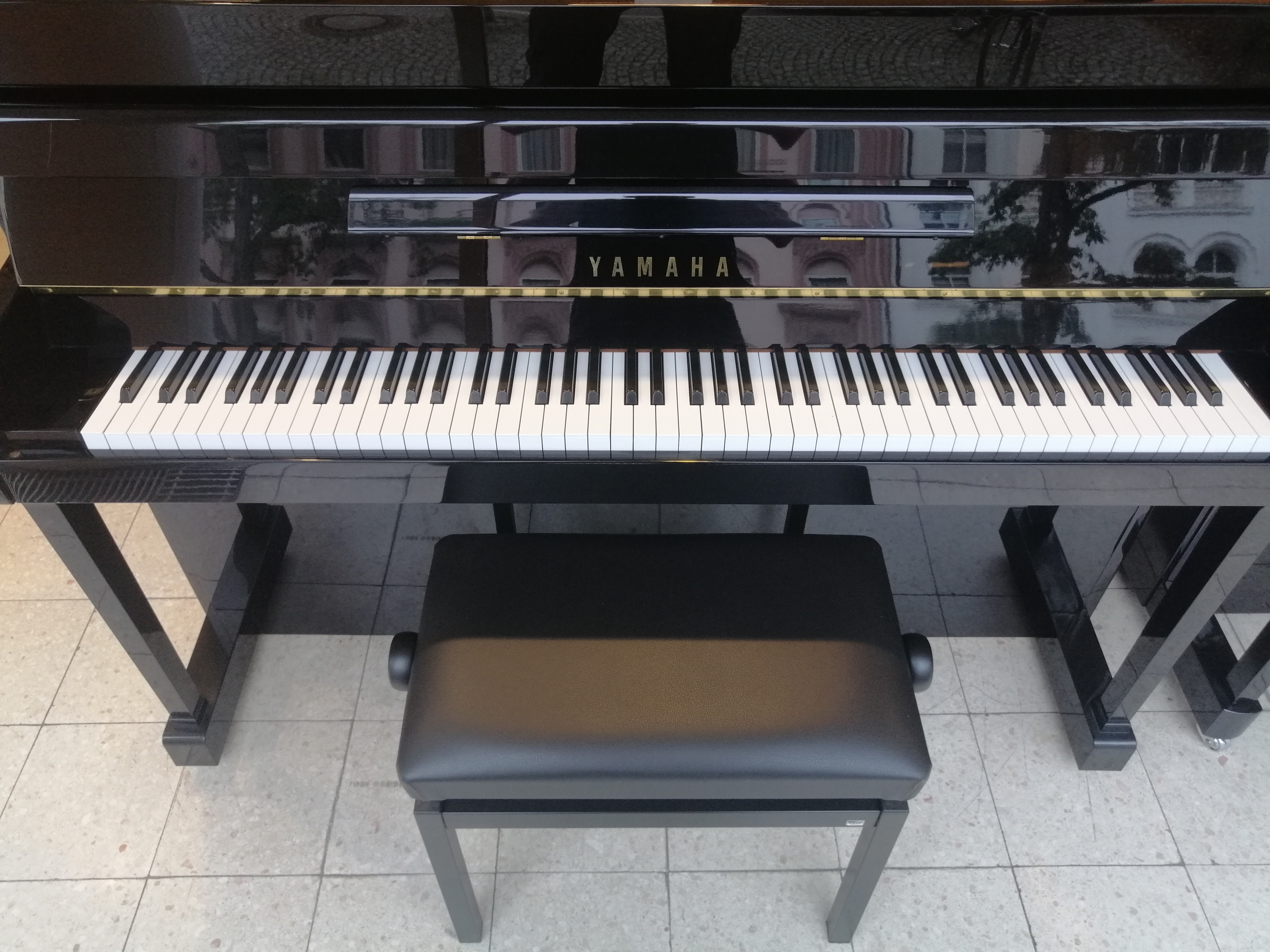Yamaha Klavier mit Klavierbank auf Fliesenboden