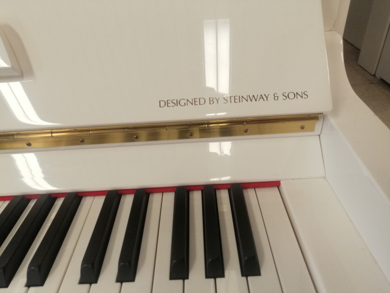 Weiße Klaviertastatur und Gehäuse mit Aufschrift 'Designed by Steinway & Sons'