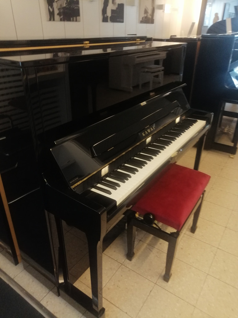 Schwarzes Kawai Klavier mit rotem Klavierhocker in einem Musikgeschäft, aufgenommen am 29.08.2026