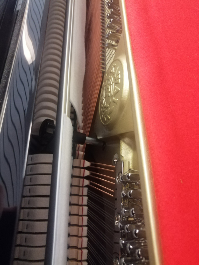 Detailansicht der Mechanik und Saiten eines Klaviers mit Filz und Metallteilen
