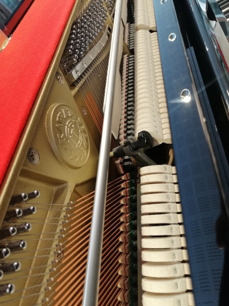 Detailaufnahme des Innenlebens eines Klaviers mit Saiten, Hämmern und Mechanik