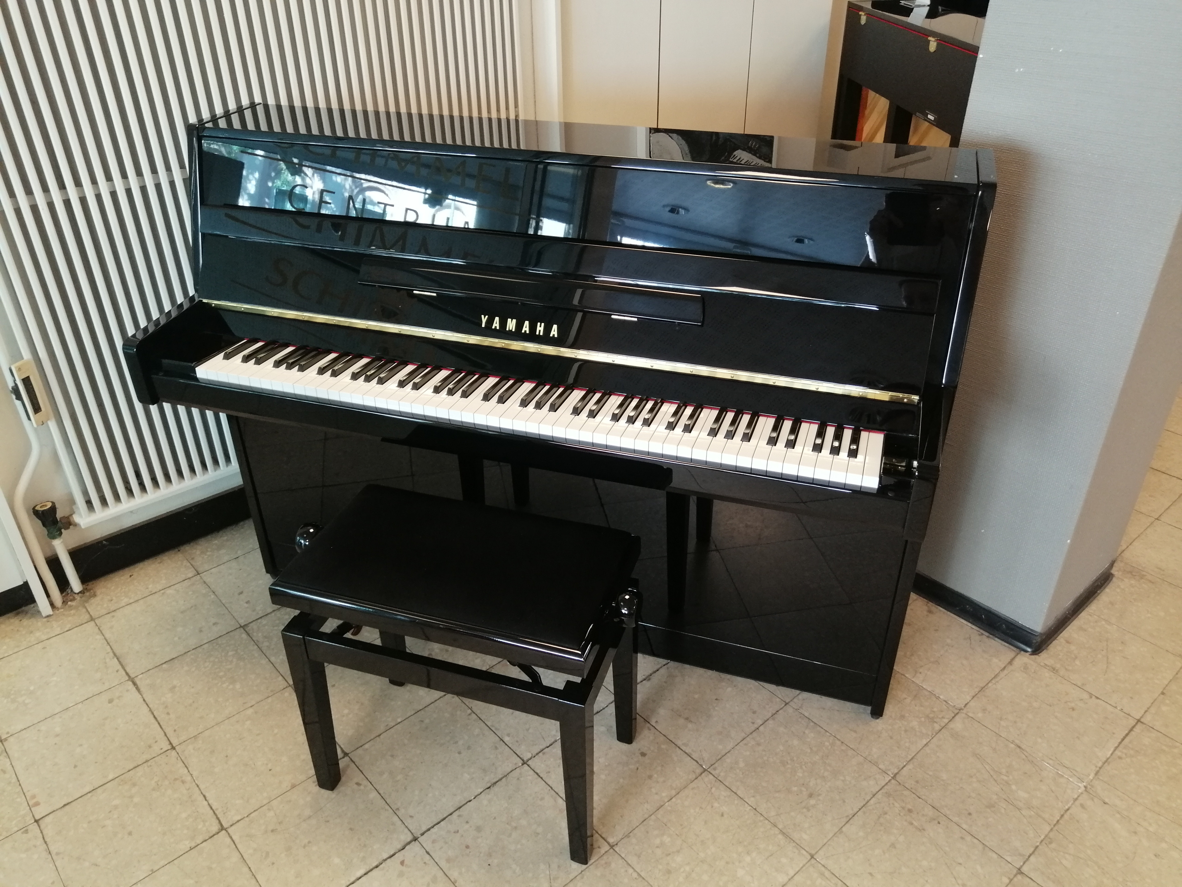 Schwarzes Yamaha Klavier mit Klavierbank in einem Musikgeschäft