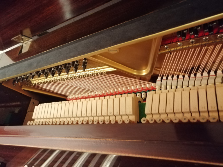 Detailansicht der Mechanik eines Klaviers mit Saiten und Hämmern