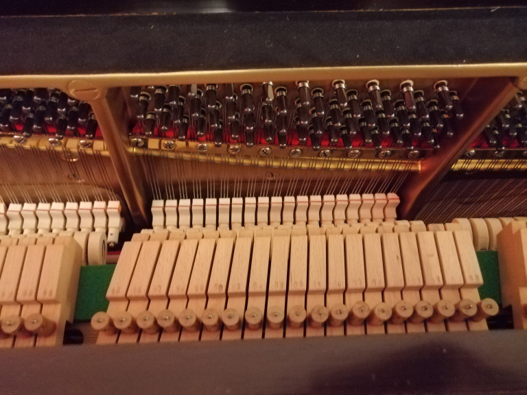 Detailansicht der Mechanik und Saiten eines Klaviers von oben